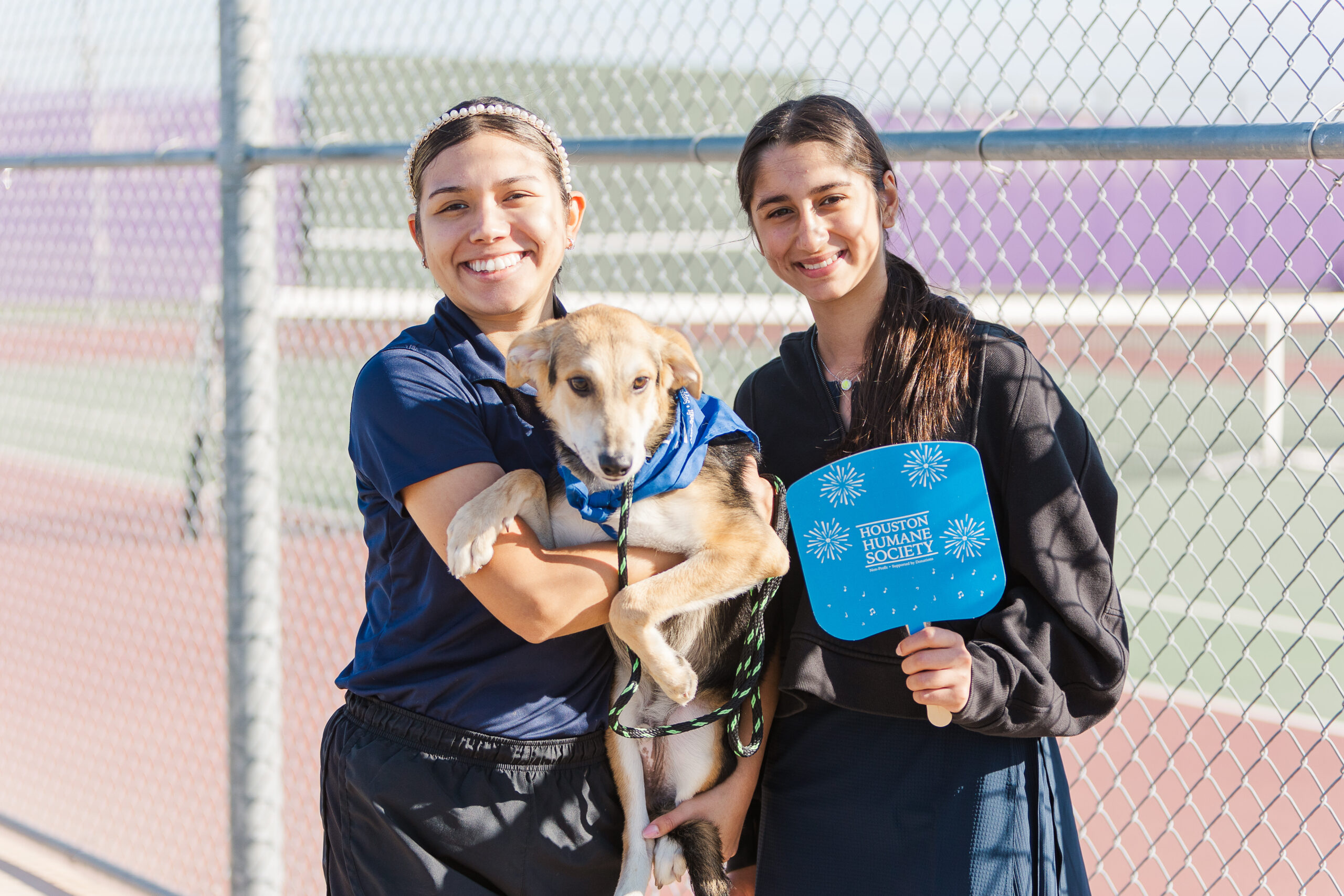 Two participants with a dog at the Houston Humane Society charity tennis event